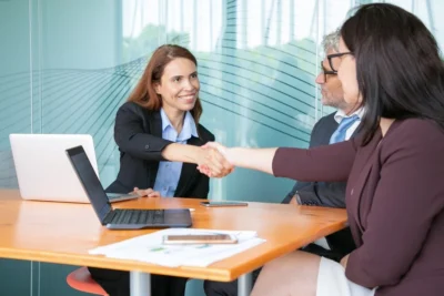 Reunião de negócios com profissionais se cumprimentando, promovendo networking e parcerias em ambiente corporativo.