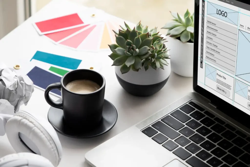 Imagem mostrando um ambiente de trabalho com um layout de site, contendo elementos visuais como amostras de cores, um laptop, uma caneca de café e suculentas. A disposição dos elementos ilustra como o layout do seu site pode impactar sua performance no Discover.