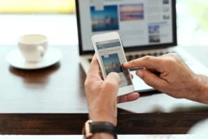 Pessoa acessando notícias através de smartphone e computador, ilustrando as mudanças no consumo de notícias com a inteligência artificial.
