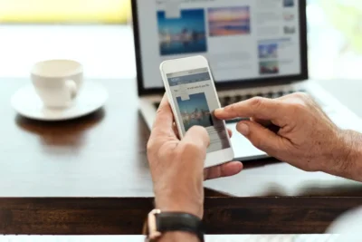 Pessoa acessando notícias através de smartphone e computador, ilustrando as mudanças no consumo de notícias com a inteligência artificial.