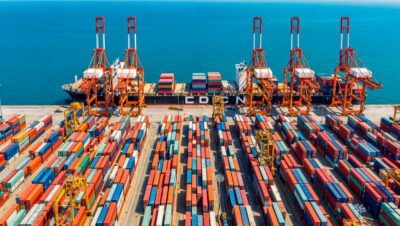 Imagem de contêineres sendo embarcados num navio, simbolizando as exportações do segmento de metais e minérios.