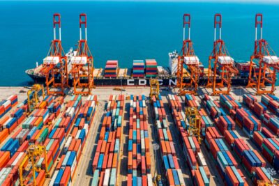 Imagem de contêineres sendo embarcados num navio, simbolizando as exportações do segmento de metais e minérios.