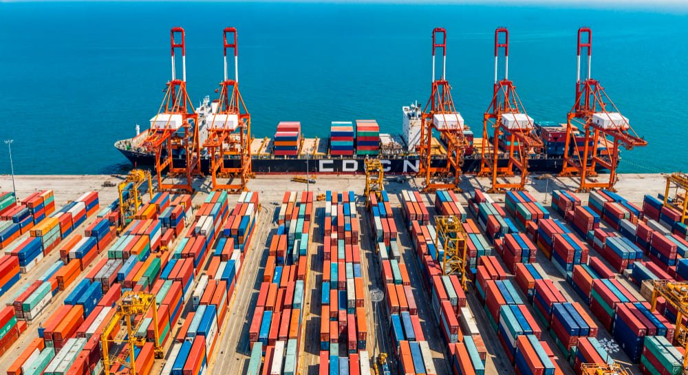 Imagem de contêineres sendo embarcados num navio, simbolizando as exportações do segmento de metais e minérios.