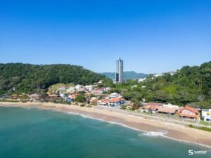Vista aérea de praia em Santa Catarina, com faixa de areia, mar e área urbana