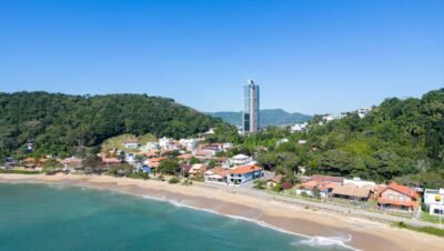 Vista aérea de praia em Santa Catarina, com faixa de areia, mar e área urbana