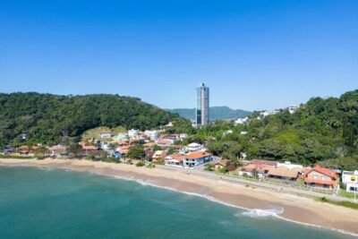 Vista aérea de praia em Santa Catarina, com faixa de areia, mar e área urbana